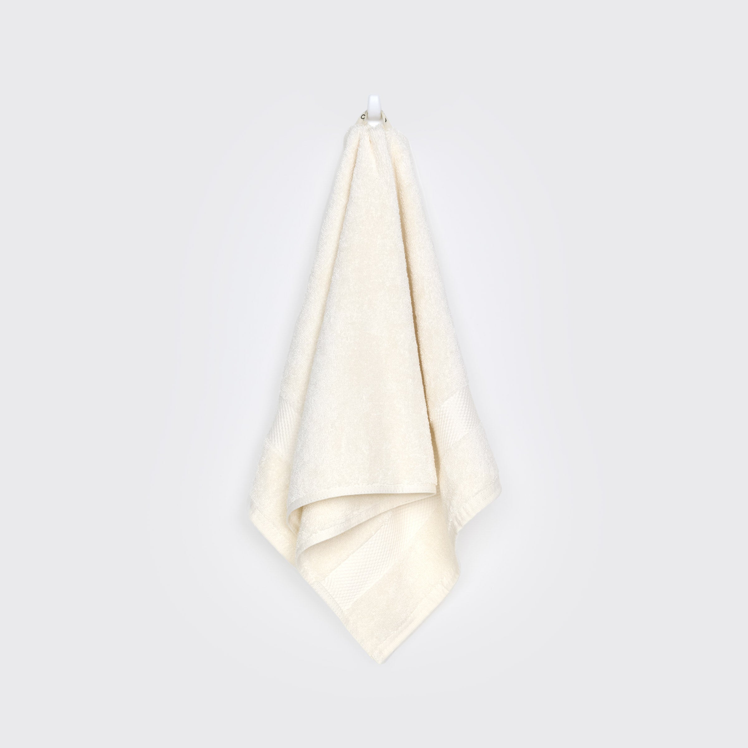 organic-cotton-hand-towel-in-natural-colour-hanging-on-a-wall-by-sojao