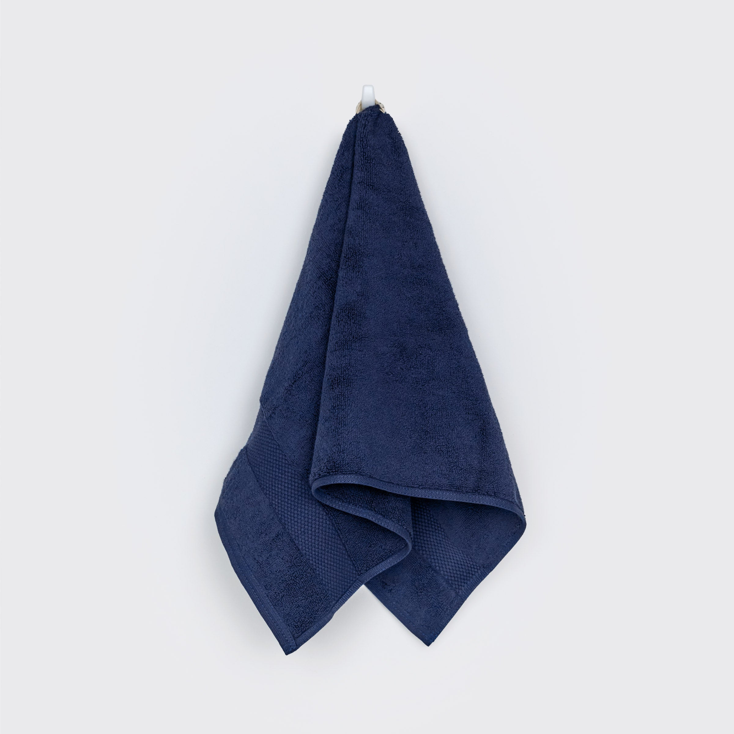organic-cotton-hand-towel-in-navy-colour-hanging-on-a-wall-by-sojao