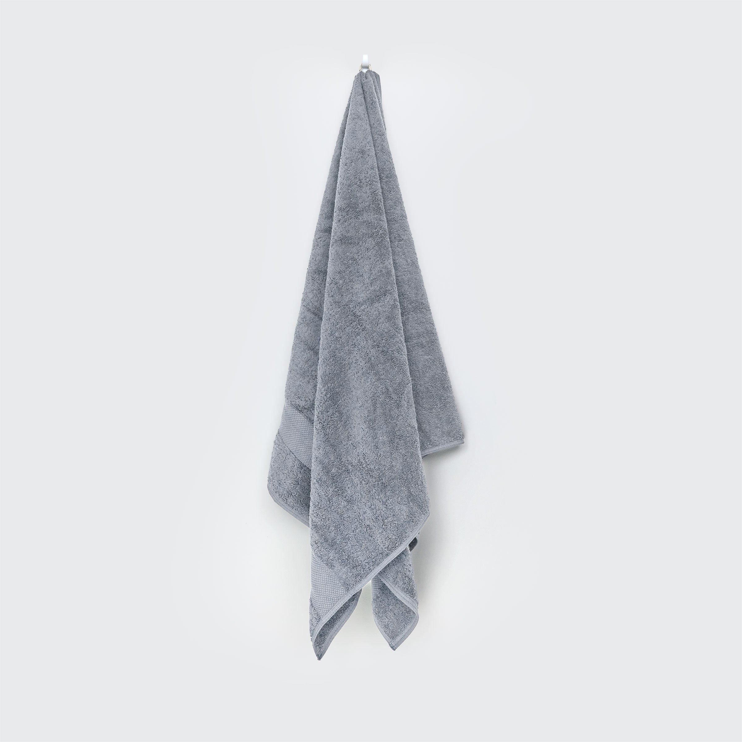 organic-cotton-bath-towel-in-forst-colour-hanging-on-a-wall-by-sojao