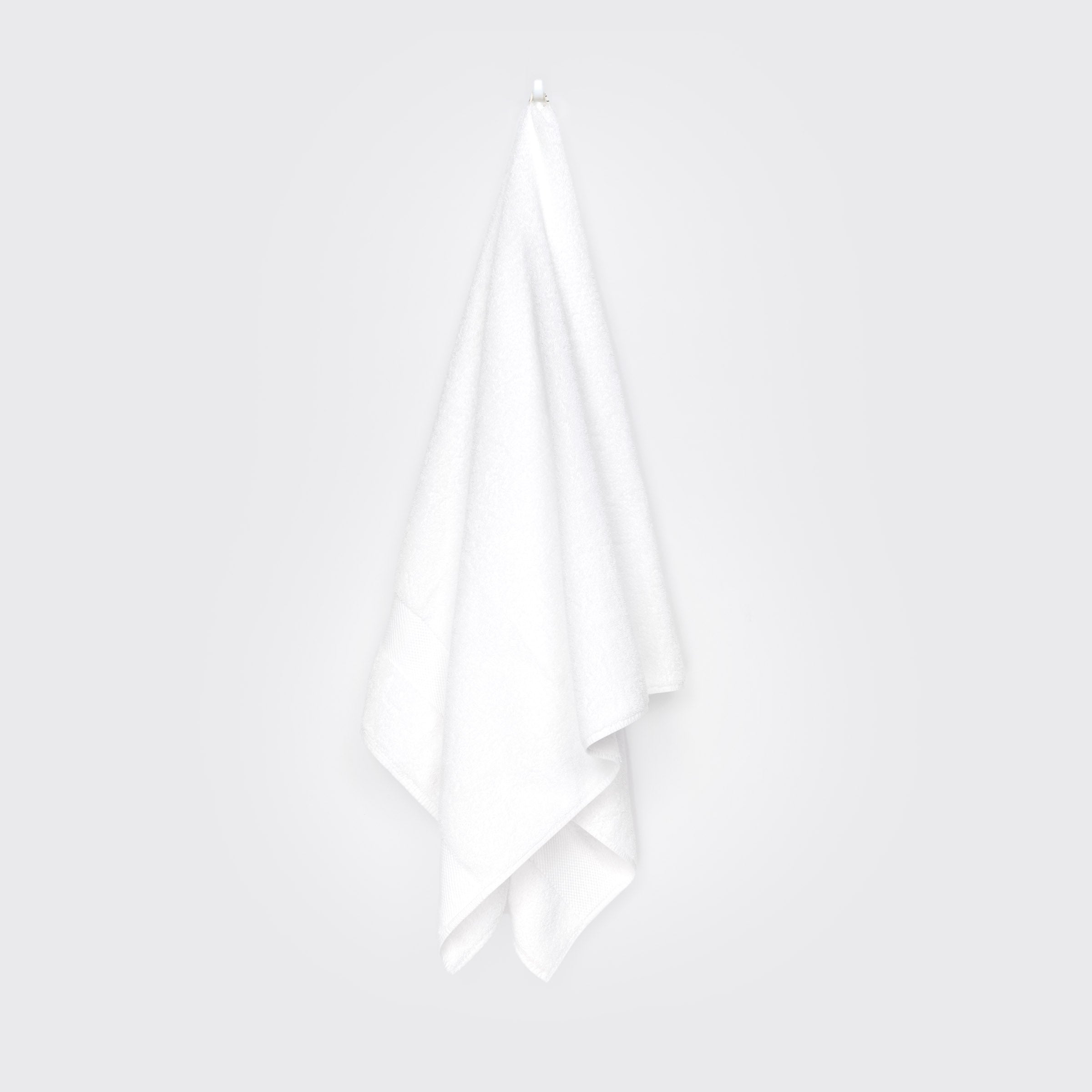 organic-cotton-bath-towel-in-white-colour-hanging-on-a-wall-by-sojao