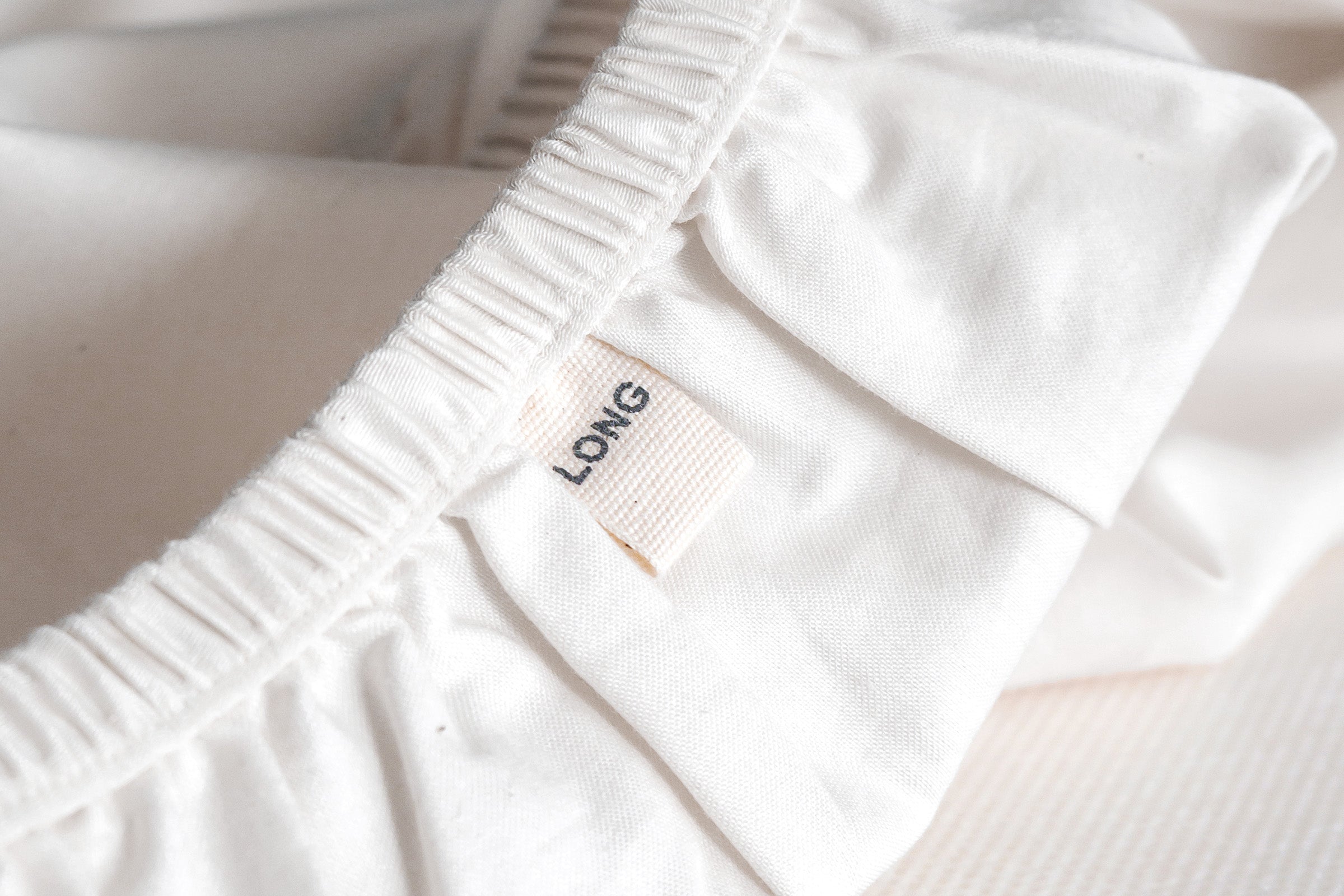 white-organic-crisp-baby-cot-fitted-sheet-close-up-shot-of-long-side-label-by-sojao.jpg