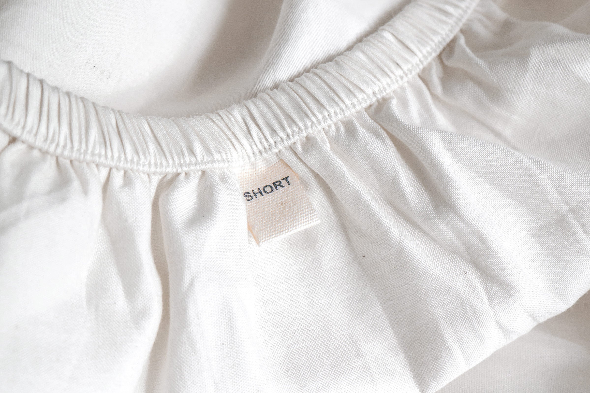 white-organic-crisp-baby-cot-fitted-sheet-close-up-shot-of-short-side-label-by-sojao.jpg