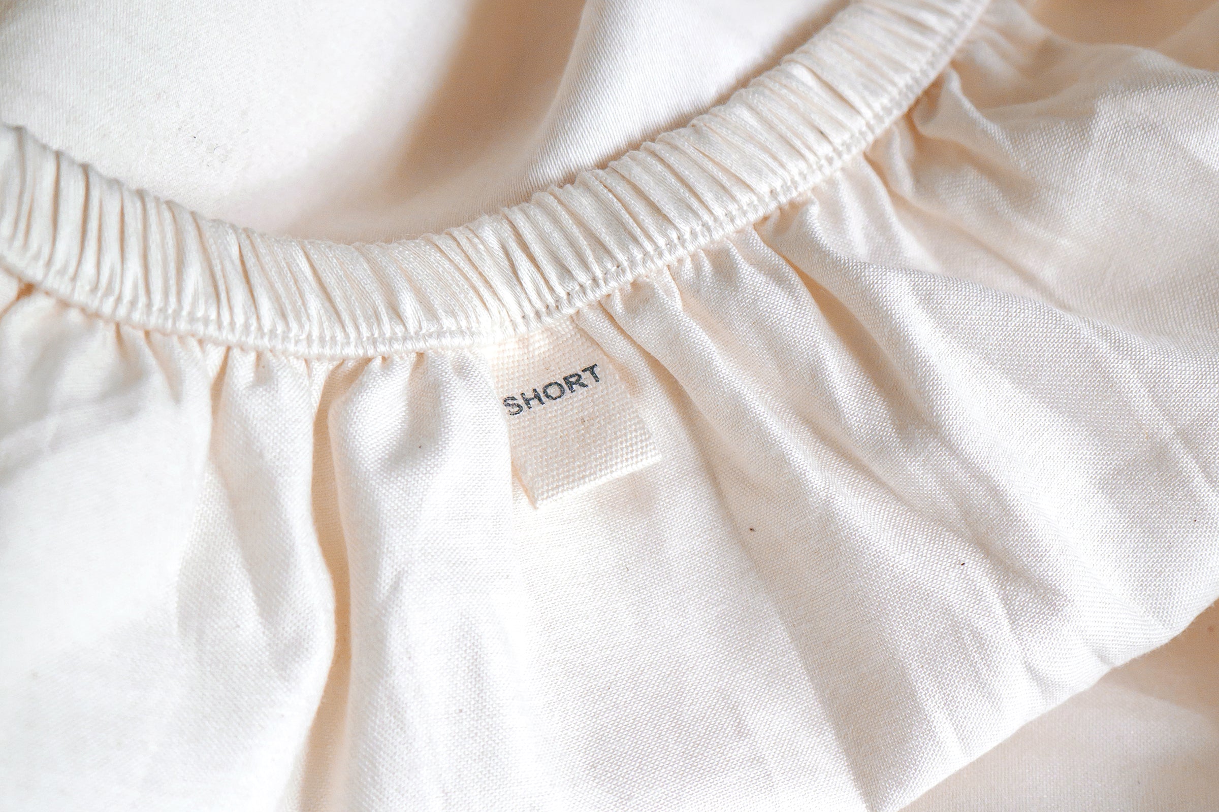 white-organic-classic-baby-cot-fitted-sheet-close-up-shot-of-short-label-by-sojao.jpg